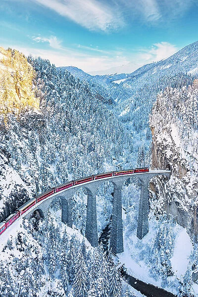 Aerial view of train traveling on Landwasser viaduct across the snowy frozen woods, Filisur, Graubunden canton, Switzerland