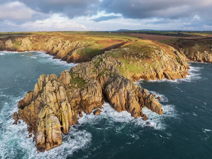 Framed Print : Aerial view of Treryn Dinas headland and Logan Rock near Porthcurno on the west coast of Cornwall, England. Winter (January) 2025