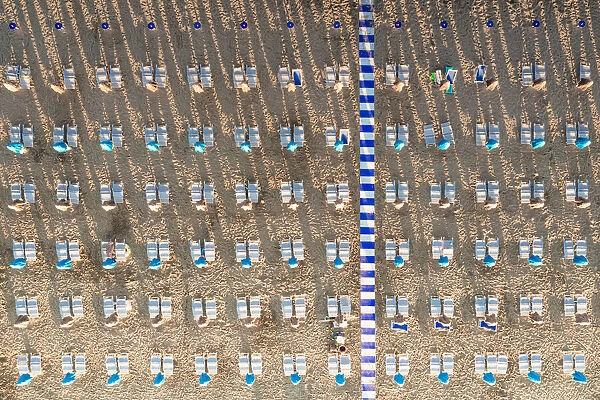 Aerial view of white sunbeds in a row on empty sand beach in summer, Vieste