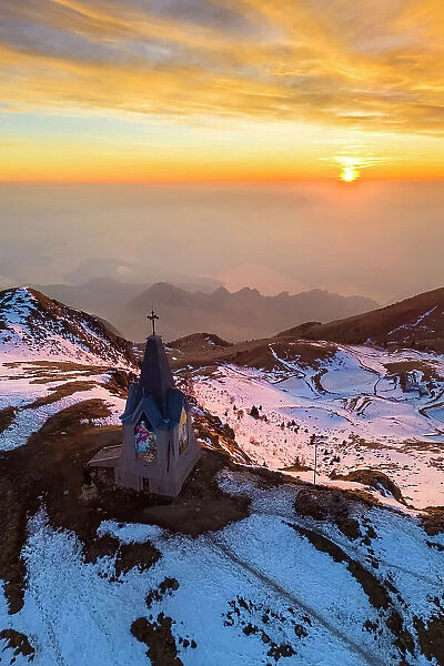 Aerial view of a winter sunset over Monumento al Redentore chapel on the top of Mount Mount Guglielmo. Zone, Brescia province, Lombardy, Italy