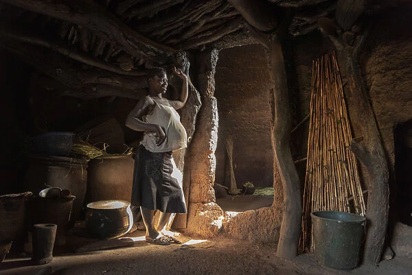Africa, Benin, Boukumba. Pregnant woman standing inside a Tata Somba