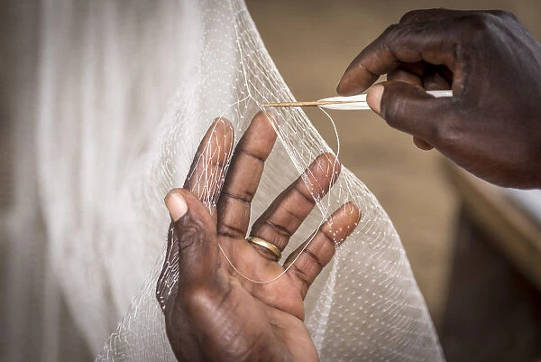 Africa, Benin, Grand Popo. Man repairing his fishing net. Detail