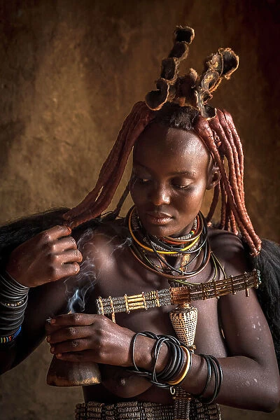 Africa, Namibia, Kamanjab. A himba woman preparing the herbal smoke to deodorize herself