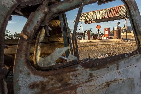 Africa, Namibia, Keetmanshop. Old petrol station seen through a rusty car door