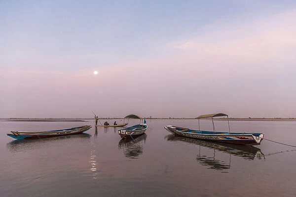 Africa, Senegal, Sine-Saloum-Delta. Moon rising above fishing boats in the delta