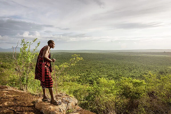 Africa, Tanzania, Manyara Region. Msai man on a rock overlooking the landscape towards the plain of Tarangire National park