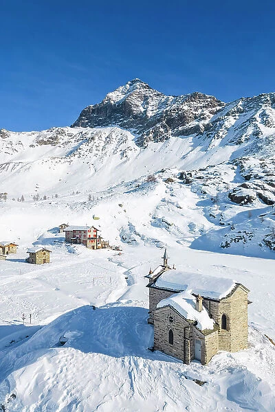 Alpe Prabello with Santuario Madonna della Pace and Mount Disgrazia in the background in winter. Lanzada, Valmalenco, Valtellina, Sondrio district, Lombardy, Italy, Europe