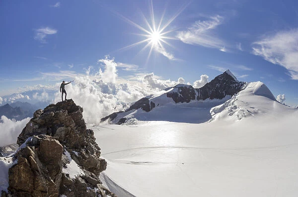 Alpinist over a rock near Balmenhorn bivac looking to Lyskamm peak with sun in backlight