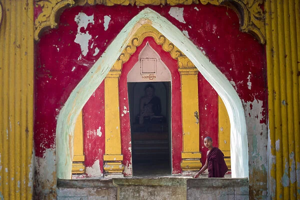 Amarapura, Mandalay region, Myanmar. Monk through the window of a colorful pagoda