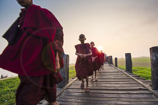 Amarapura, Mandalay region, Myanmar. Monks walking on the U Bein bridge at sunrise