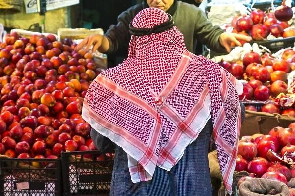Arab man waerinf Keffiyeh buying apples in market, Amman, Jordan