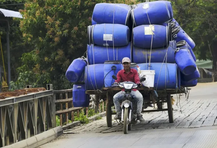 Framed Print : Asia, South East Asia, Cambodia, motorbike rider with a heavy load crossing a bridge