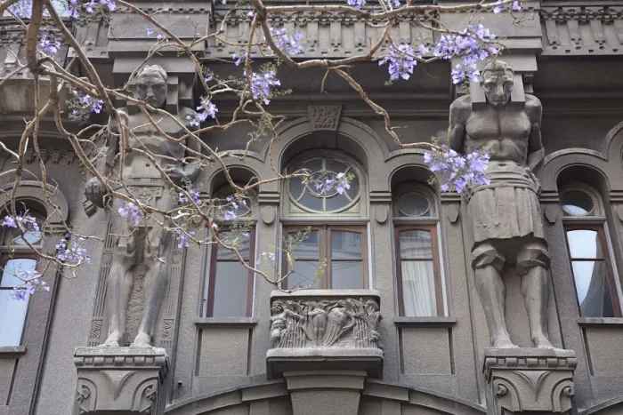 Framed Print : Atlases'over the main facade of the Otto Wulff buiding with a Jacaranda flowering plant in foreground, Monserrat, Buenos Aires, Argentina. The building was built in Jugendstil style