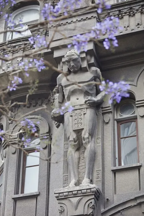 Framed Print : One of the Atlas'over the main facade of the Otto Wulff buiding with a Jacaranda flowering plant in foreground, Monserrat, Buenos Aires, Argentina. The building was built in Jugendstil style
