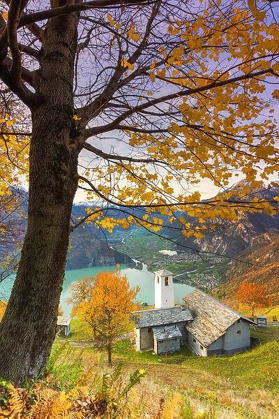 Autumn colors at the Foppaccia church at sunset with view on the Novate Lake and valley