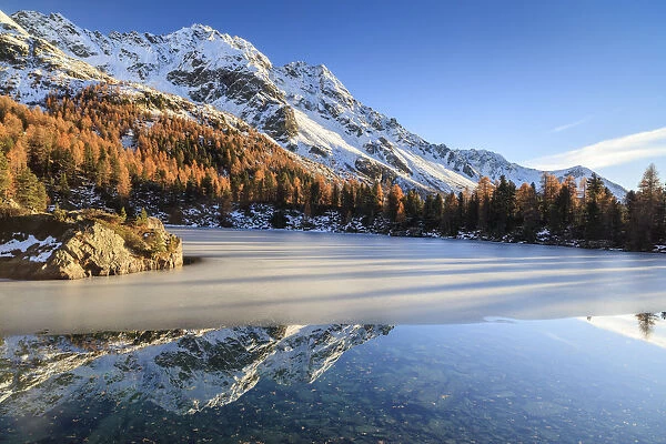 Autumn reflections at Saoseo Lake still partially frozen Poschiavo Valley Canton of