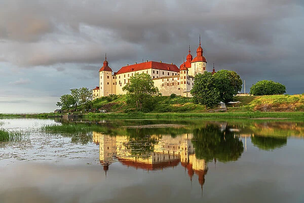 Baroque Lacko castle and its reflection in the water of Vanem lake at sunset, Kallandso island, Lidkoping municipality, Gotaland, Sweden