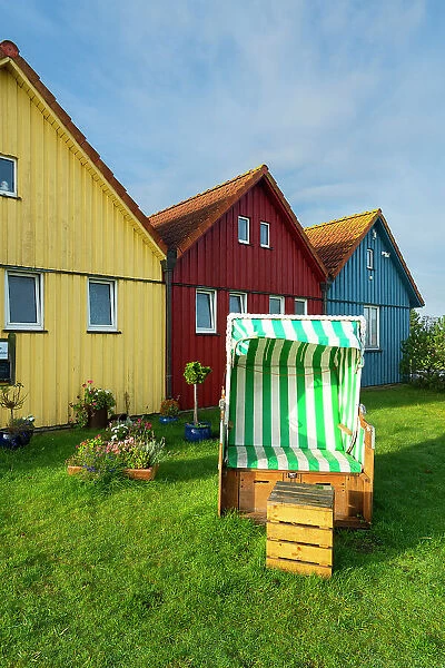 Beach chair in front of colorful houses of Seefohrerhus restaurant, Wittdun harbor, Amrum island, Nordfriesland, Schleswig-Holstein, Germany