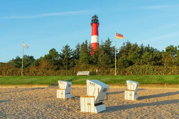 Framed Print : Beach chairs near German flag and Hornum lighthouse in background at sunrise, Hornum beach, Sylt, Nordfriesland, Schleswig-Holstein, Germany