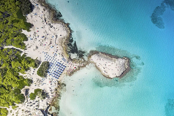 Beach umbrellas on white sand beach by turquoise sea from above, Punta della Suina
