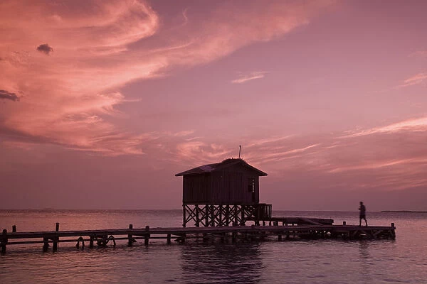 Belize, Tobaco Caye, Man on pier at sunset