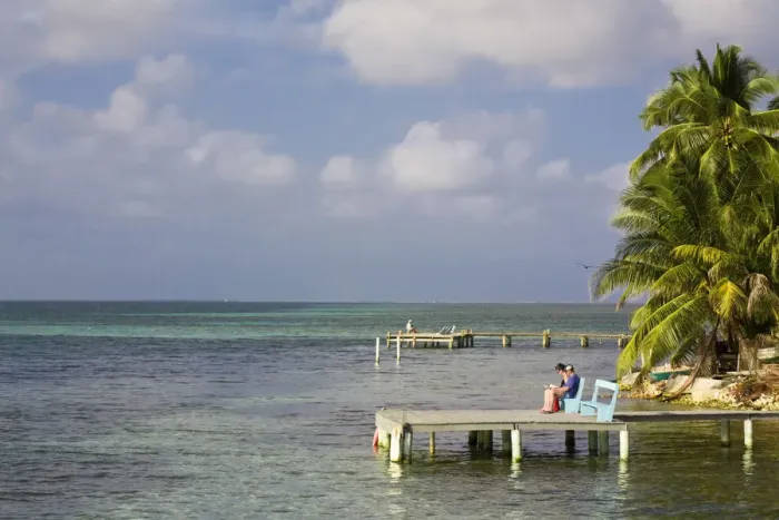 Framed Print : Belize, Tobaco Caye, Tourists sitting on pier reading Framed Print : Belize, Tobaco Caye, Tourists sitting on pier reading