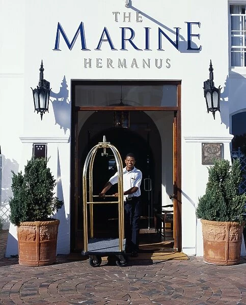 A bellboy pushes the luggage trolley through the Hotel entrance
