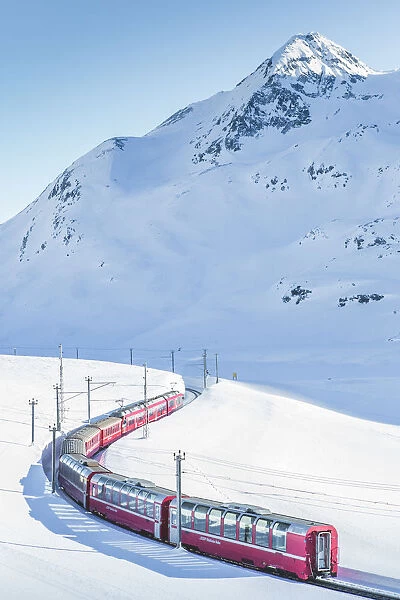 Bernina Express red train passing Lago Bianco in a scenic winter mountain landscape