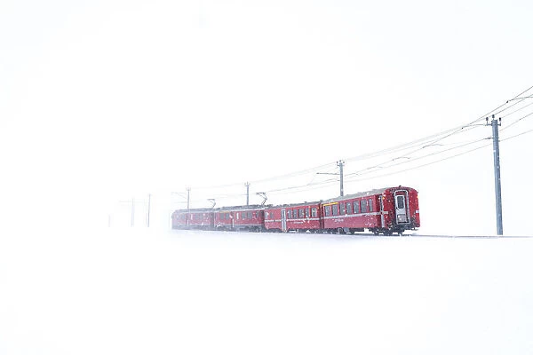 Bernina Express during a snowfall at Bernina Pass, Graubunden, Engadine, Switzerland