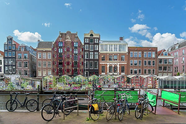 Bicycles standing against typical houses and floating flower market near Singel canal, Amsterdam, Netherlands