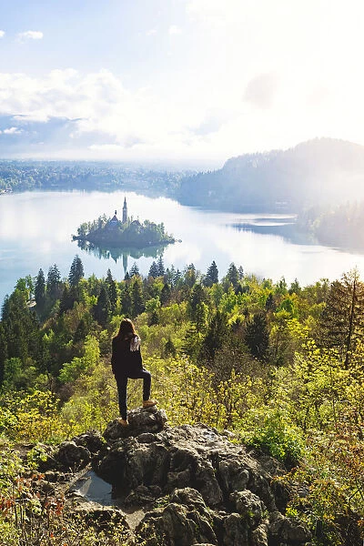 Bled Lake, Slovenia. Sunrise over the misty island from a high viewpoint with hiker