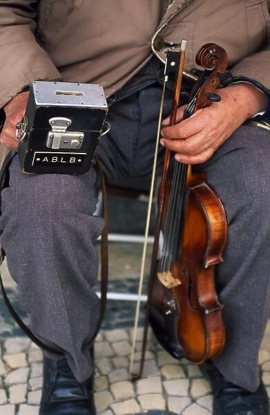 A blind street musician holds his violin in one hand