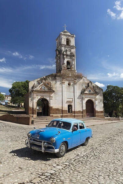 Blue classic car passes old church, Trinidad, Sancti Spiritus Province, Cuba