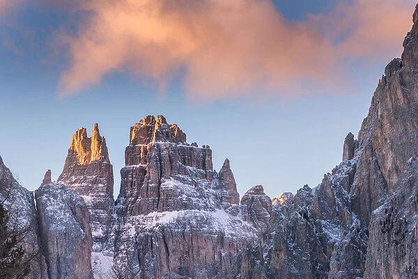 Blue sky and red clouds on the rocky peaks of the Rosengarten massif in winter Dolomites