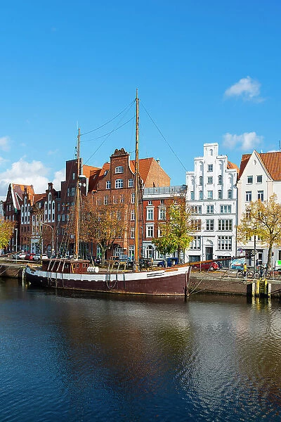 Boat anchored on Trave river and houses with traditional gables in background, Lubeck, UNESCO, Schleswig-Holstein, Germany