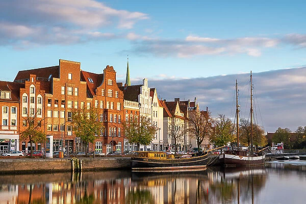 Boats anchored on Trave river and houses with traditional gables in background at sunset, Lubeck, UNESCO, Schleswig-Holstein, Germany