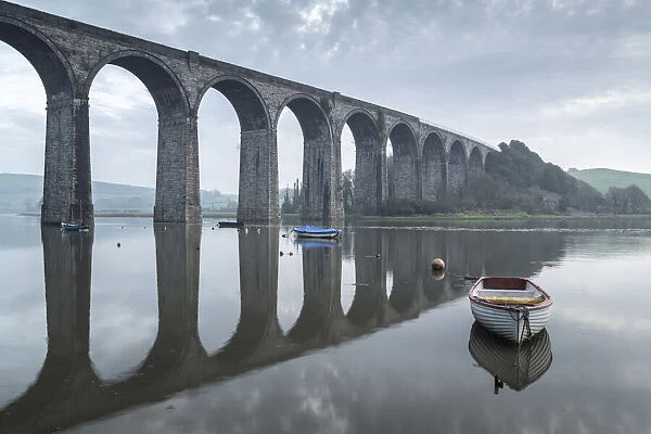 Boats moored beneath the towering arches of St Germans viaduct at dawn