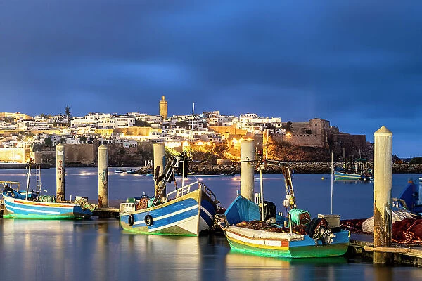Boats moored along the waterfront with the old medina on background at dusk, Rabat, Morocco