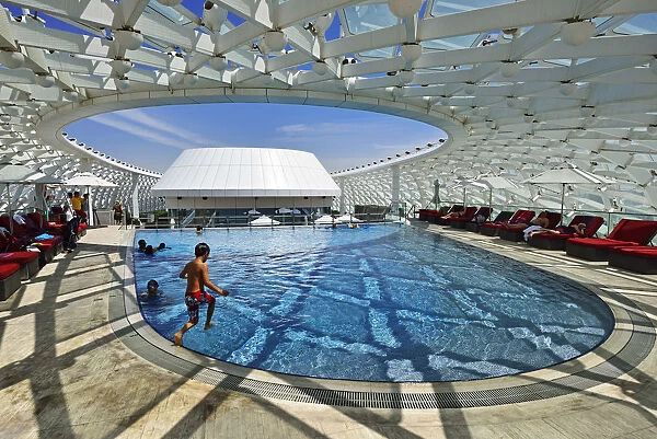 A boy jumps into the swimming pool of the Yas Marina Circuit Formula 1 race track