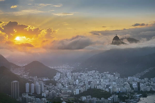 Brazil, Rio de Janeiro. Urban skyline and landscape with Christ statue, Botafogo neighborhood and mountains at sunset. Dramatic clouds, no people, copy space