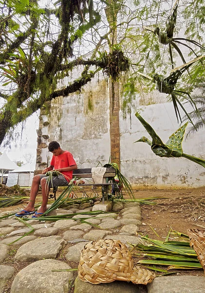 Brazil, State of Rio de Janeiro, Paraty, Boy making Palm Leafs Wattles on the Street