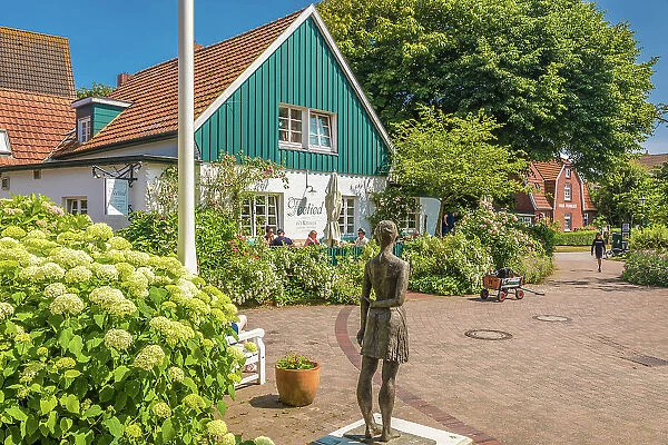 Bronze statue island girl and tea room in the village center of Spiekeroog, East Frisian Islands, East Frisia, Lower Saxony, Germany