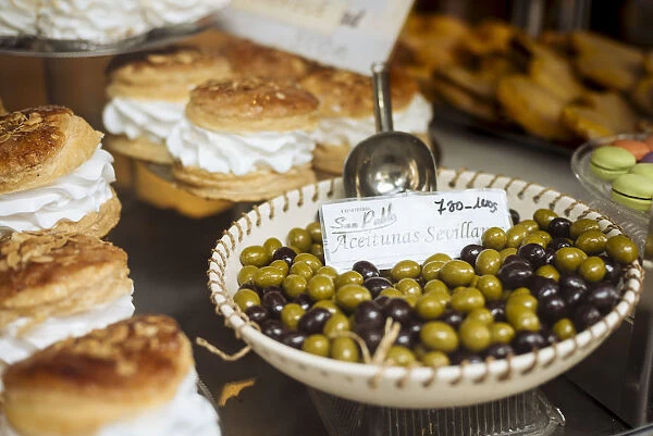 Cakes and Olives on display in shop window, Seville, Andalucia, Spain