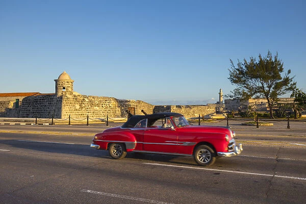 Car driving past the Castillo de San Salvador de la Punta, Havana, Cuba
