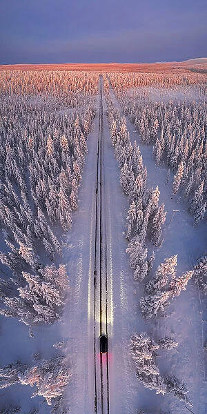 a car with headlight on travelling empty road at dawn, Pallas-Yllastunturi National Park, Muonio, Lapland, Finland