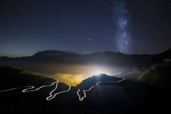 Car trails on the winding road leading to Nivolet Pass and milky way in the background
