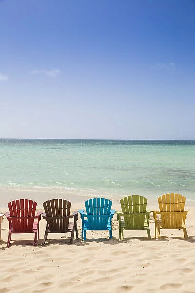 Caribbean, Netherland Antilles, Aruba, A row of colourful wooden deck chairs on Palm
