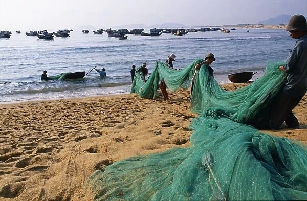 Carrying fishing nets up the beach after the days work