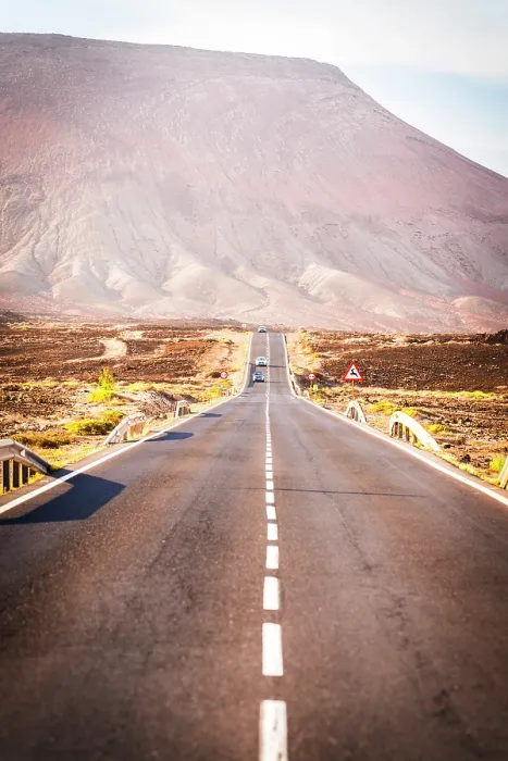 Framed Print : Cars driving on an asphalt road in the barren landscape towards volcanic mountains, Corralejo, Fuerteventura, Canary Islands, Spain Framed Print : Cars driving on an asphalt road in the barren landscape towards volcanic mountains, Corralejo, Fuerteventura, Canary Islands, Spain