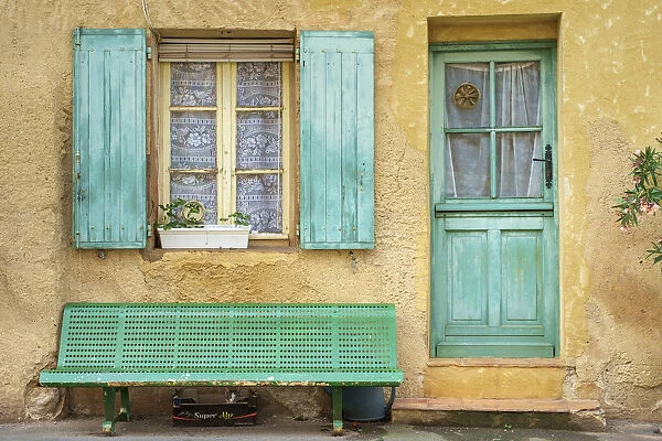 Cat sleeping under a bench in front of a house in Roussillon, Vaucluse